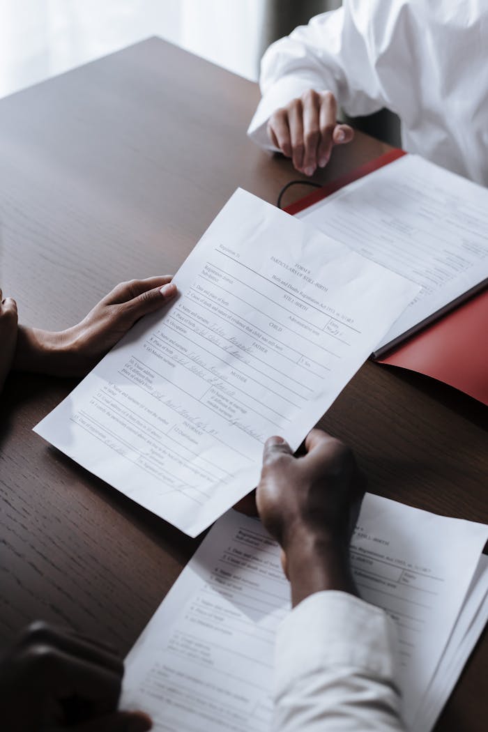 Adults reviewing legal documents on a wooden desk indoors, highlighting professional collaboration.
